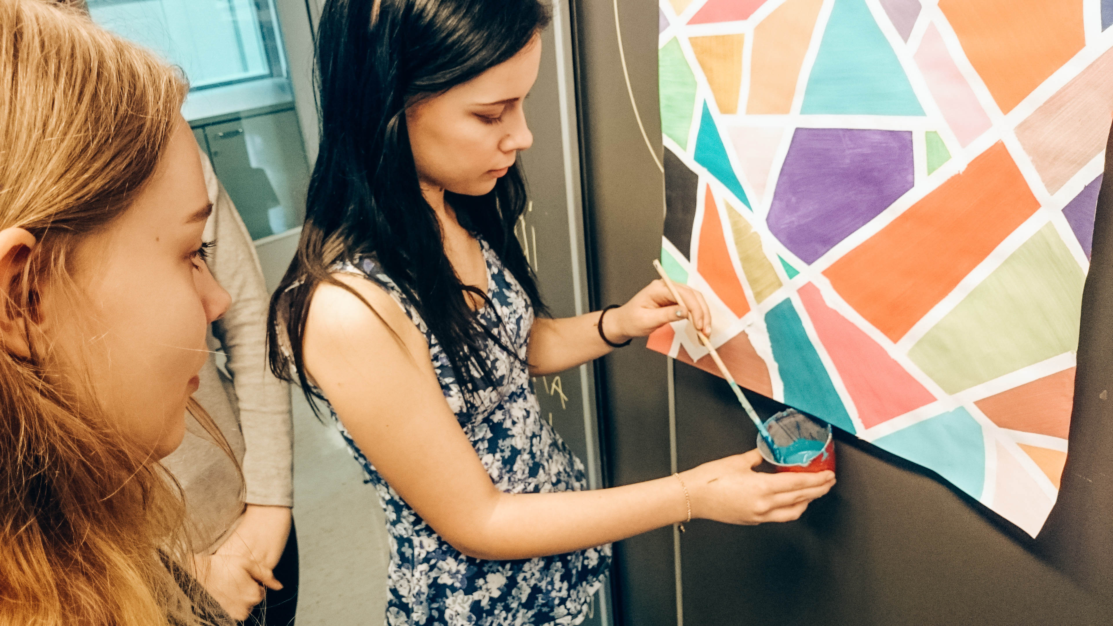 芬蘭學生將草圖作品貼在牆壁上，並拿起畫筆補色。