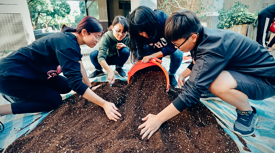 四名國中學生在校園內鋪蓋土壤種植植物