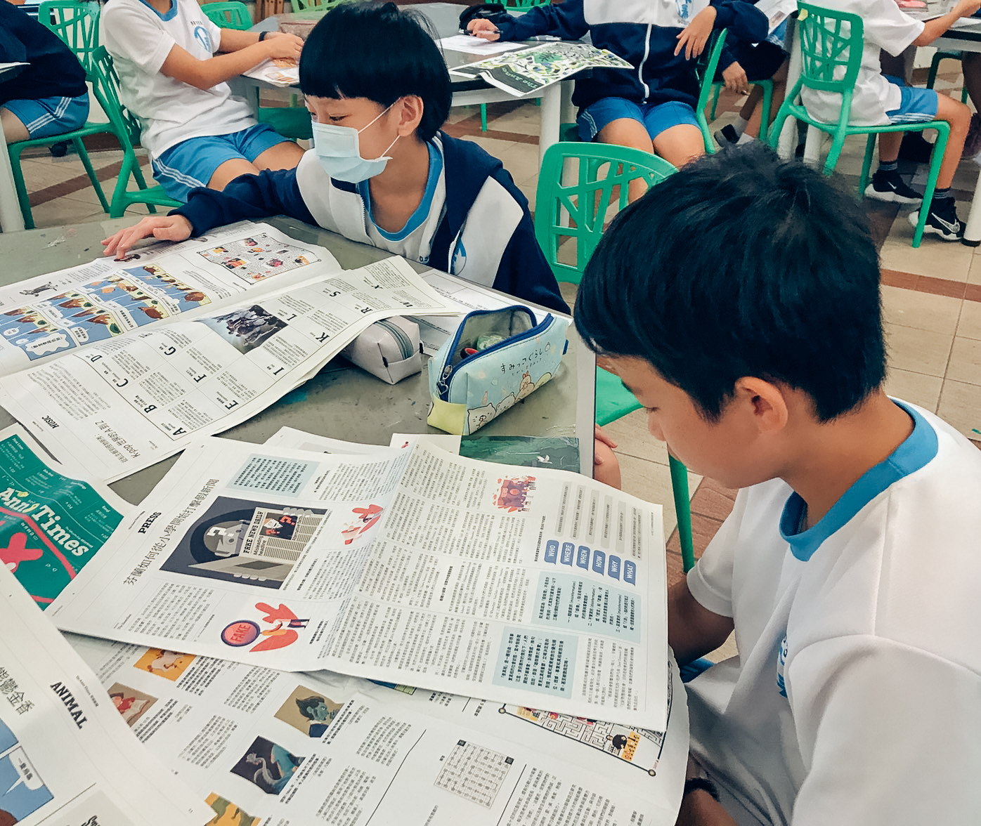 兩名男同學在六角形書桌上閱讀安妮新聞