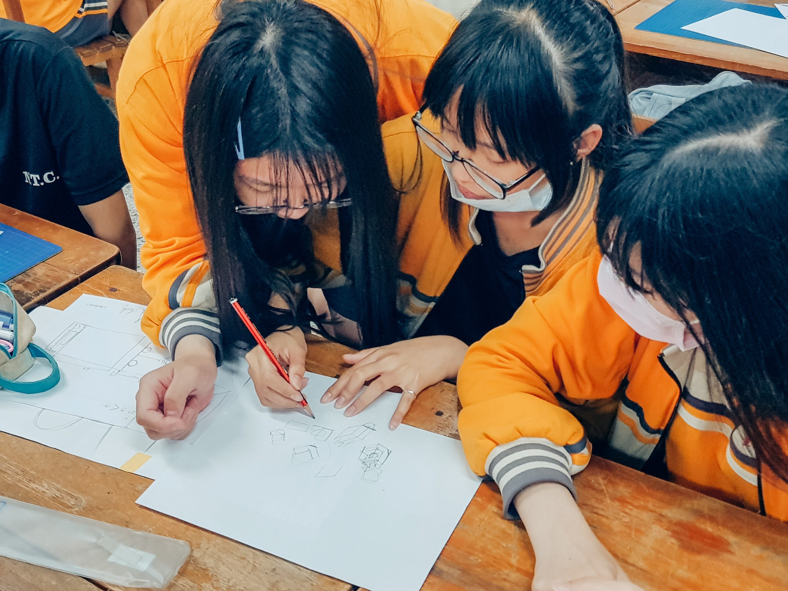 三名女學生在圖紙上做設計討論