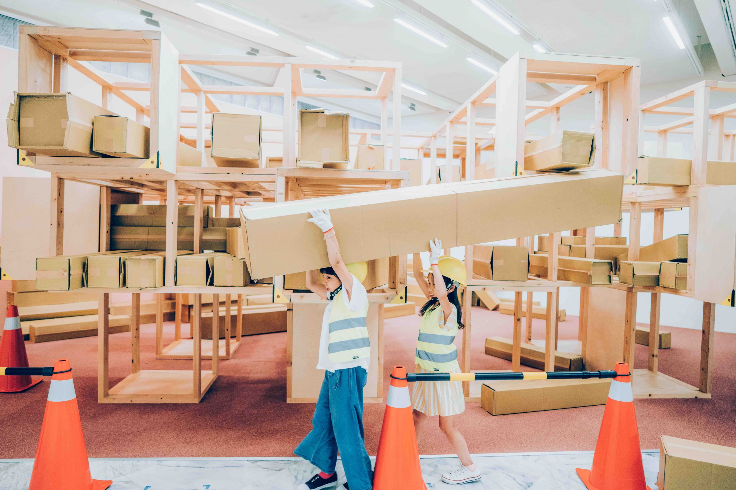 臺北市立美術館兒童教育藝術中心「建築的70_」中兩名孩童戴著安全帽在搬運大紙箱